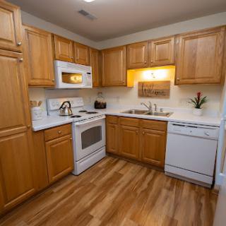 A modern kitchen featuring wooden cabinets, white appliances, and a warm ambiance.