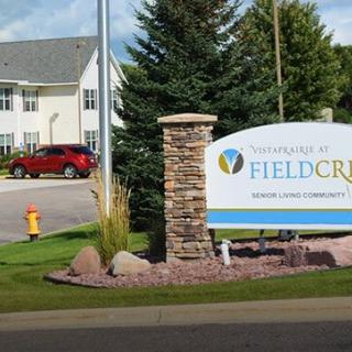 Entrance sign for Fieldcrest community with landscaped surroundings and residential buildings.
