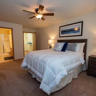 A cozy and well-decorated bedroom featuring a king size bed, ceiling fan, and soft neutral tones.