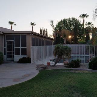 A serene backyard view featuring a screened patio and swimming pool, framed by palm trees at dusk.