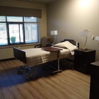 A hospital room featuring a bed, chair, and window with natural light.