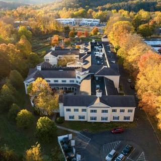Aerial view of a building surrounded by autumn trees and a parking lot during sunset.