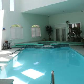 An indoor swimming pool with a calm and relaxing atmosphere, featuring surrounding plants and lounge chairs.