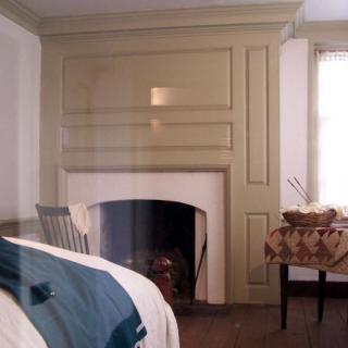 A cozy bedroom with a fireplace, featuring warm tones and classic furniture.