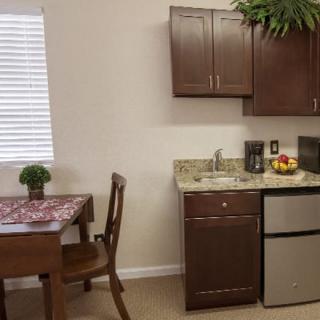 A cozy kitchen and dining area with wooden cabinets, a small table, and modern appliances.