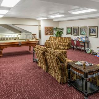 A cozy living area featuring patterned sofas, a pool table, and framed artwork on the walls.