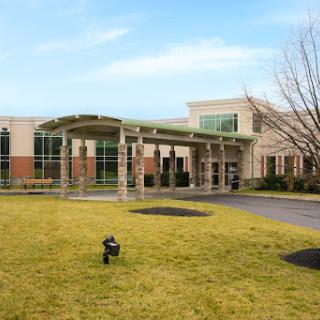 A modern facility with a welcoming entrance framed by lush greenery.