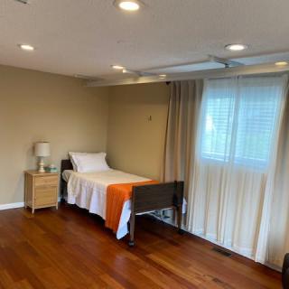 A minimalist bedroom with a single bed, wooden floors, and soft lighting.
