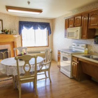 A cozy kitchen with a dining area, featuring wooden cabinets and a fireplace.
