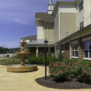 A scenic outdoor view of a building with a fountain and well-maintained garden.