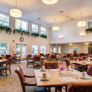 A spacious dining area with neatly arranged tables and chairs, featuring elegant lighting and decor.