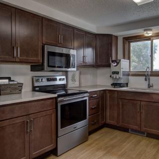 A modern kitchen featuring dark wooden cabinets, stainless steel appliances, and a bright window.