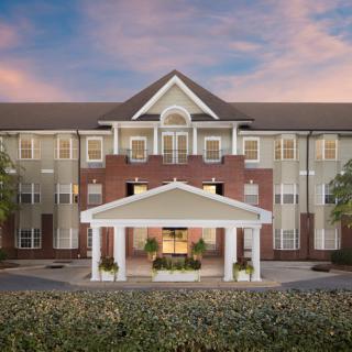 A frontal view of a residential building with a prominent entrance and landscaped surroundings.