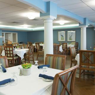 A well-arranged dining area with neatly set tables and wooden chairs, featuring blue walls and elegant decor.