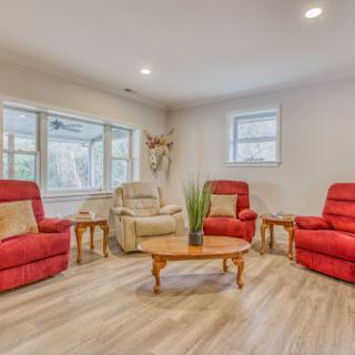 A cozy living room featuring red recliner chairs and a wooden coffee table, illuminated by natural light.