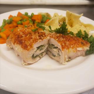 A gourmet meal featuring stuffed chicken breast, served with a side of pasta and mixed vegetables.
