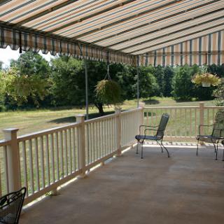 A spacious patio area with comfortable seating and a retractable awning, surrounded by lush greenery.