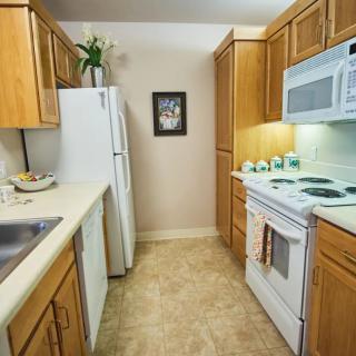 A compact kitchen with wooden cabinets, appliances, and countertops.