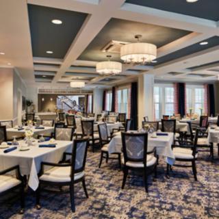 An elegant restaurant dining area with neatly arranged tables and chairs under stylish chandeliers.