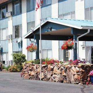 Entrance of a hotel building with hanging flower baskets and a woodpile.