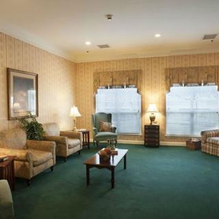A cozy living room with armchairs, a sofa, and a coffee table on a green carpet.