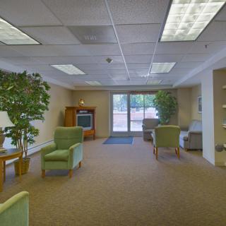 A spacious lobby with comfortable seating, a television, and greenery.