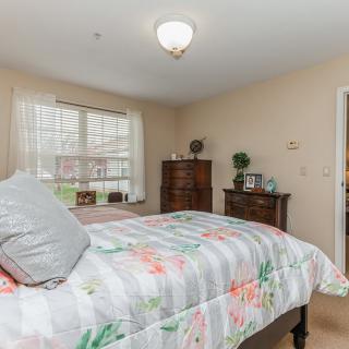 A cozy bedroom with a floral bedspread and natural lighting.