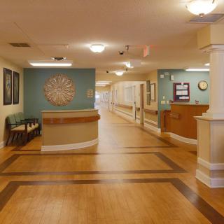A well-lit corridor in a healthcare facility, featuring a reception desk and seating area.