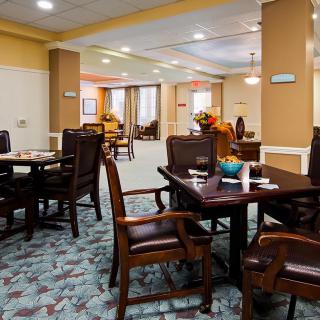 A cozy dining area with neatly arranged tables and chairs, featuring warm lighting and tasteful decor.