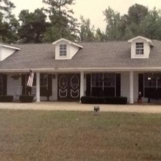 A suburban house with a front porch and spacious lawn.