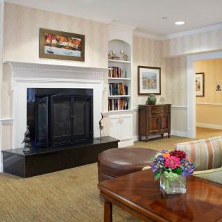 A cozy living room with a fireplace, bookshelf, and a vase of flowers on the table.