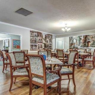 A well-furnished dining area with multiple tables and chairs, featuring elegant lighting and wooden flooring.