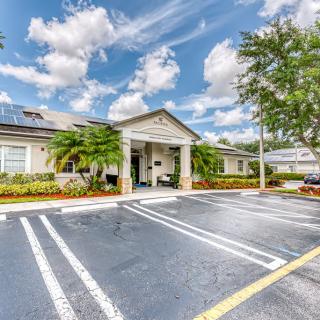 A view of a building with a parking lot under a cloudy sky.