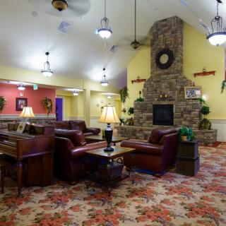 A cozy interior lounge area with a vintage design, featuring a stone fireplace, plush seating, and warm lighting.