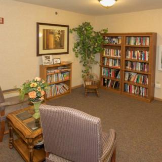 A cozy reading room with bookshelves, comfortable chairs, and a potted plant.
