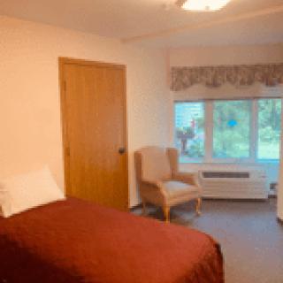 A cozy bedroom with a single bed and a chair by the window.