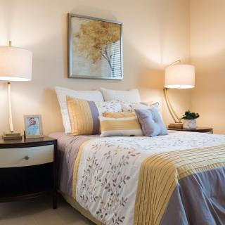 A cozy bedroom with elegant decor, featuring a neatly made bed with decorative pillows and warm lighting from bedside lamps.