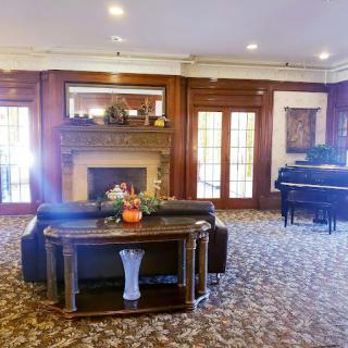 A cozy living room with a fireplace, elegant furniture, and a piano.
