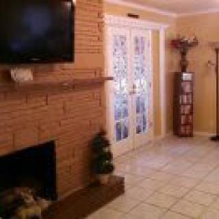 A cozy living room with a brick fireplace and mounted television, featuring French doors and elegant interior design.