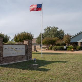 A view of a building with an American flag flying in front, surrounded by greenery.
