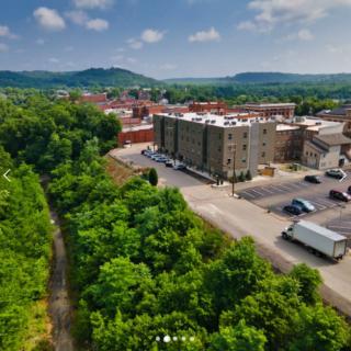 Aerial view of a small town surrounded by lush greenery and rolling hills.