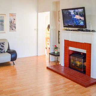 A cozy living room with a fireplace and TV, featuring wood flooring and a comfortable sofa.