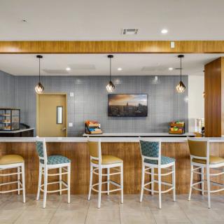 A modern bar interior with a row of stools and stylish lighting.