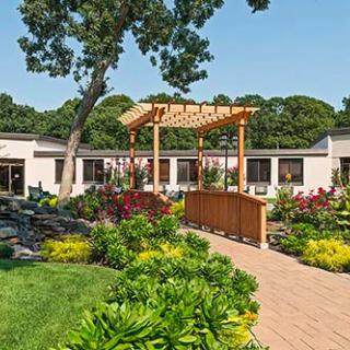 A beautifully landscaped garden featuring a wooden pergola and vibrant flower beds.