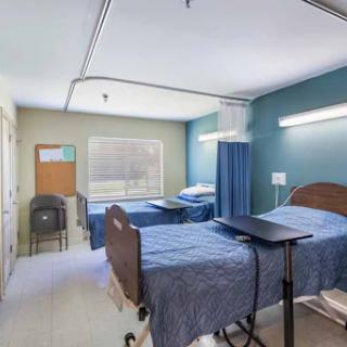 A clean and organized hospital patient room featuring two beds, medical equipment, and a bright ambiance.