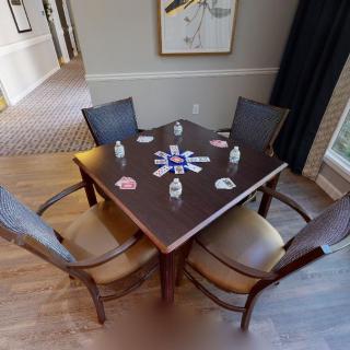 A wooden table with four chairs in a well-decorated room, featuring artwork on the wall.