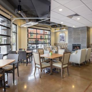 A modern restaurant interior with a spacious dining area, featuring large windows and a cozy fireplace.