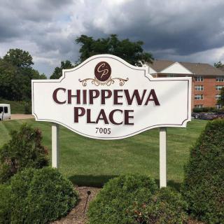 Sign for Chippewa Place in front of a building with landscaped surroundings.