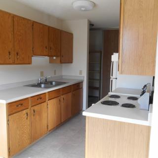 A compact kitchen with wooden cabinets and a stove.