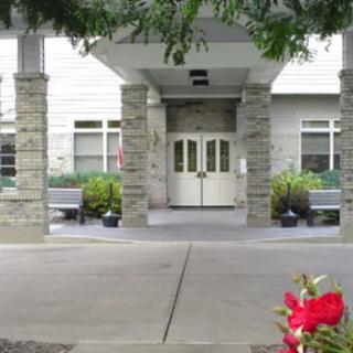 A well-maintained building entrance with stone pillars and landscaped greenery.